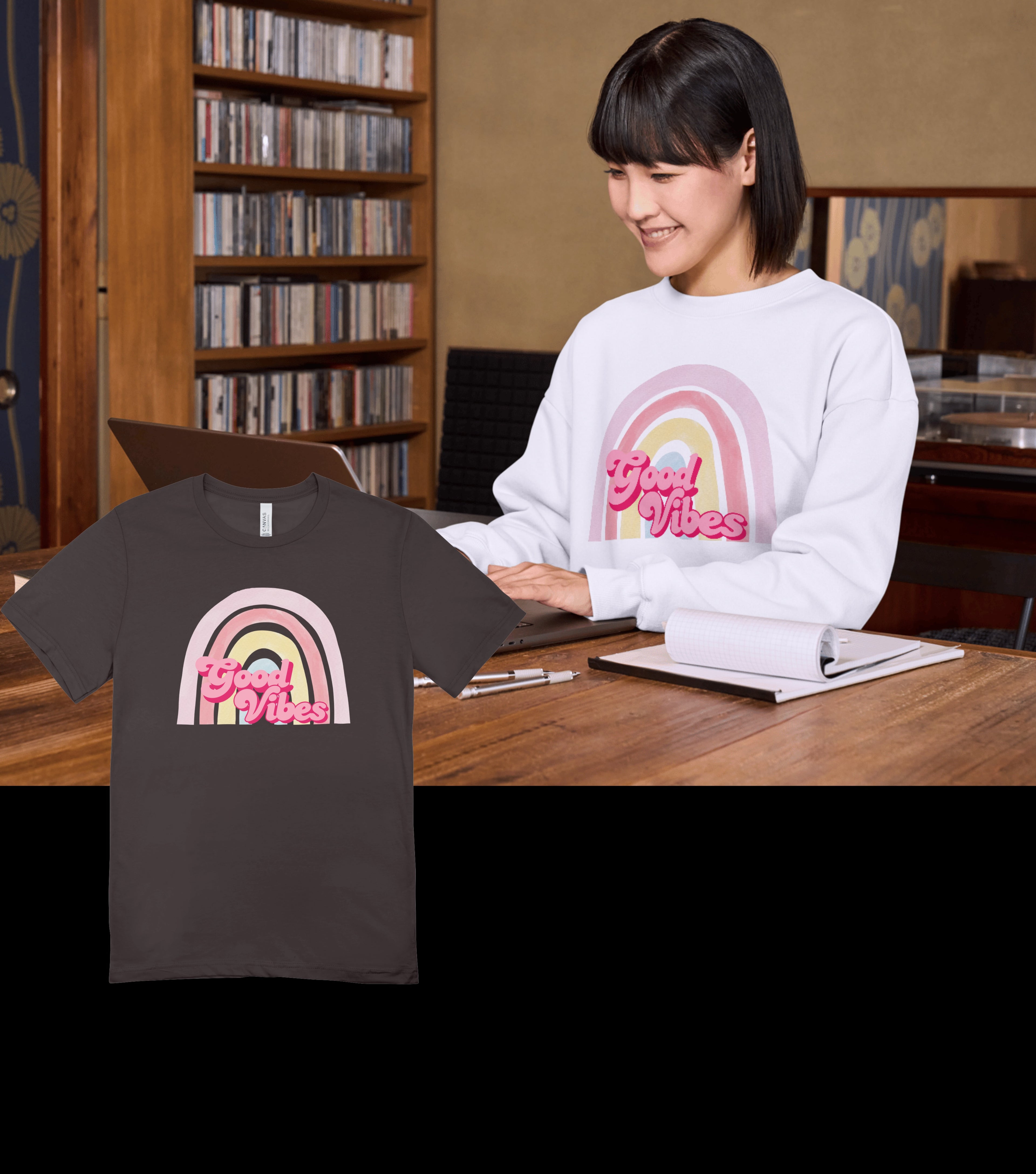 Person sitting at a desk with a t-shirt and sweatshirt featuring a rainbow design and 'Good Vibes' text.